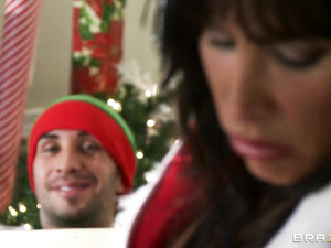 Strong guy wearing uniform on Christmas elf is enjoying passionate sex with busty brunette in sexy black lingerie and red stockings.